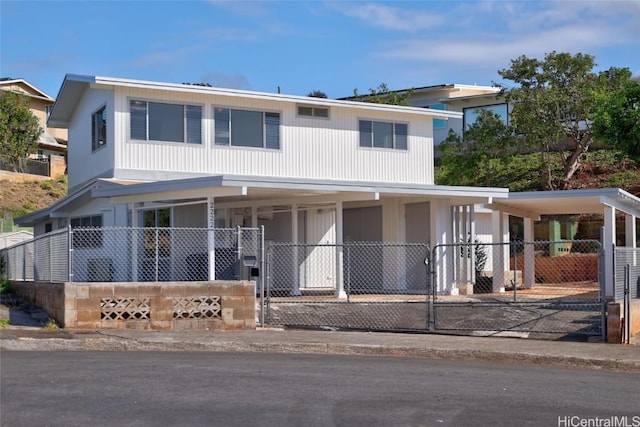 view of front of property with a porch, a fenced front yard, an attached carport, and a gate