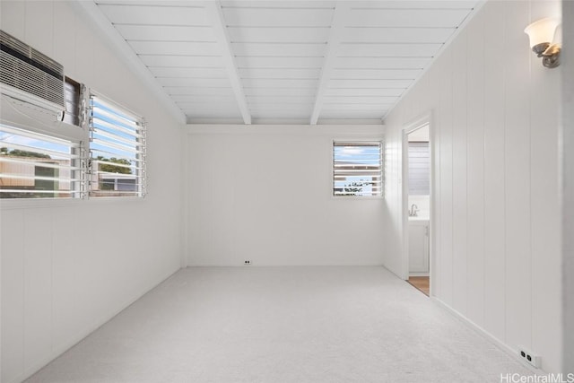 carpeted empty room featuring beam ceiling