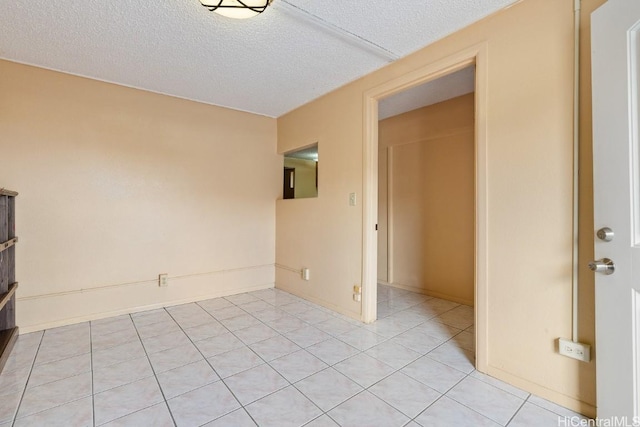 spare room with a textured ceiling and light tile patterned floors