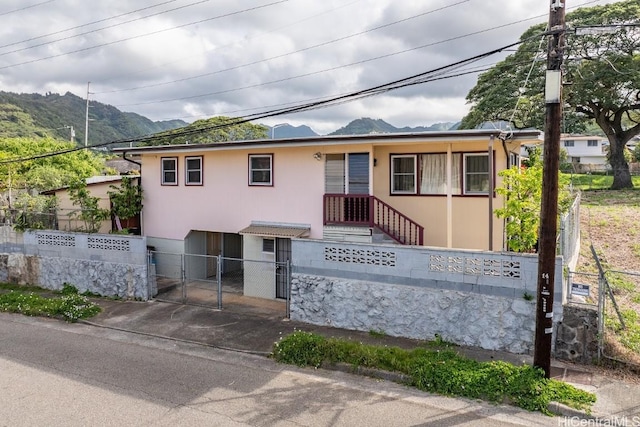 view of front of property featuring a mountain view, a fenced front yard, a gate, and stucco siding