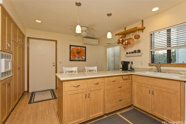 kitchen featuring stainless steel microwave, a peninsula, an AC wall unit, open shelves, and a sink