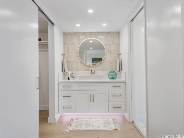 bathroom featuring recessed lighting, vanity, baseboards, and wood finished floors