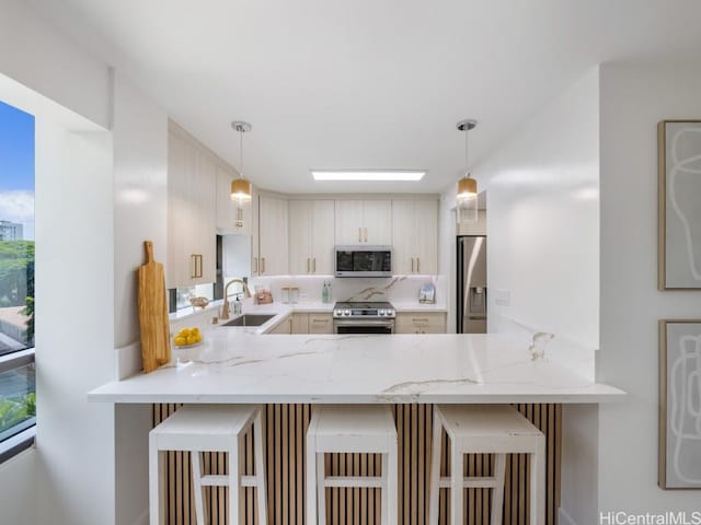 kitchen featuring appliances with stainless steel finishes, hanging light fixtures, and a breakfast bar area