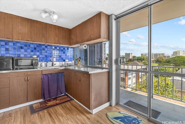 1325 Wilder Ave Unit 5, Honolulu, HI 96822 - kitchen with stainless steel microwave, a sink, light countertops, light wood-style floors, and decorative backsplash