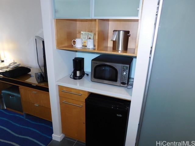 kitchen with stainless steel microwave, dishwasher, brown cabinetry, and light countertops