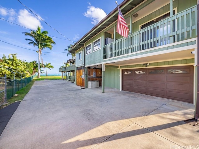 view of front of property with a garage, driveway, central AC unit, and fence