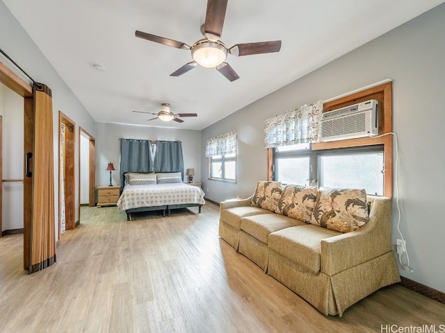 bedroom featuring a ceiling fan, a wall unit AC, baseboards, and wood finished floors