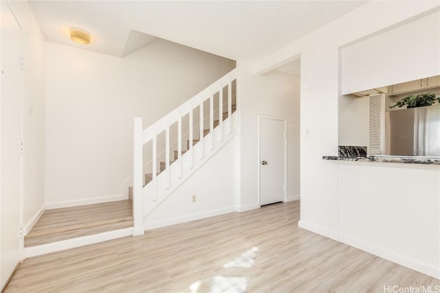 interior space featuring baseboards, stairway, and wood finished floors