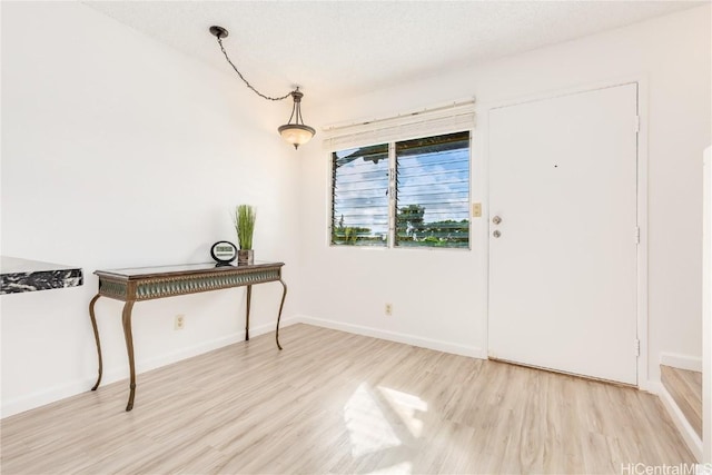 foyer featuring baseboards and wood finished floors