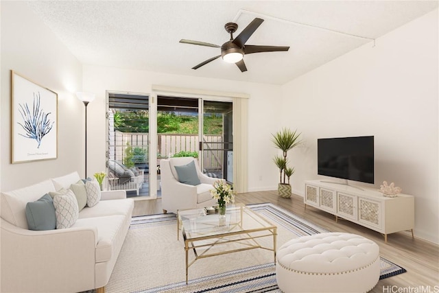 living room with ceiling fan, a textured ceiling, baseboards, and wood finished floors