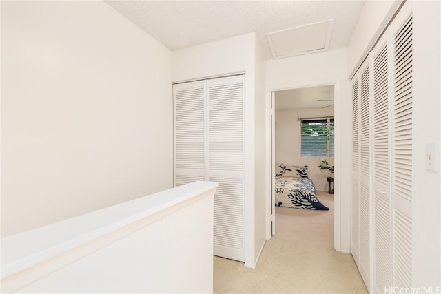 hall featuring attic access and light colored carpet