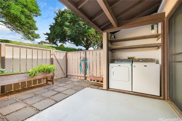 view of patio featuring washing machine and clothes dryer and fence