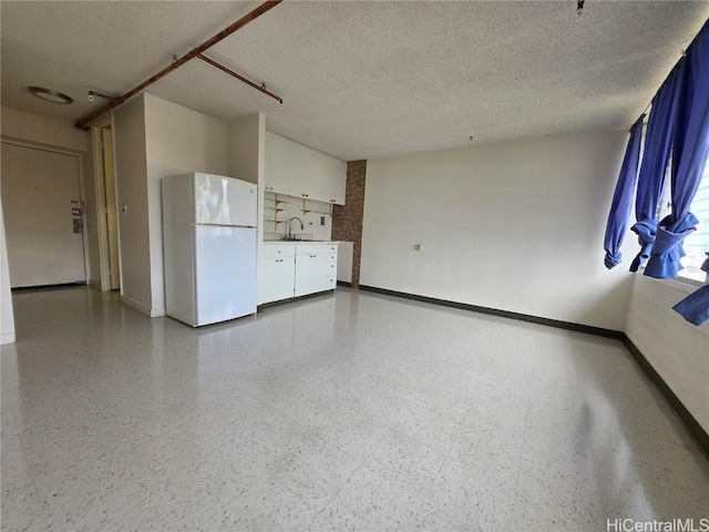 spare room with a sink, baseboards, light speckled floor, and a textured ceiling