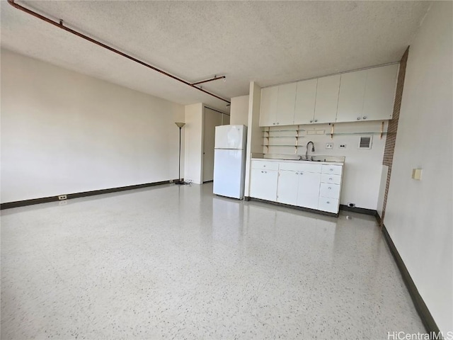 interior space with a textured ceiling, baseboards, and a sink