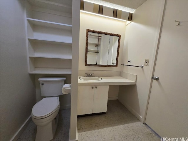 half bathroom with vanity, speckled floor, toilet, and baseboards