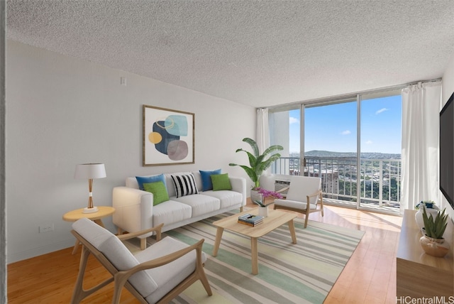 living area featuring baseboards, a textured ceiling, floor to ceiling windows, and wood finished floors