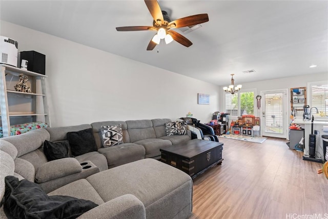 living room featuring visible vents, light wood-style flooring, and ceiling fan with notable chandelier