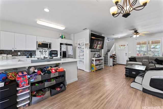 kitchen featuring white cabinetry, light countertops, open floor plan, and appliances with stainless steel finishes