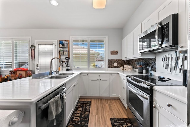 kitchen with a sink, stainless steel appliances, light wood-style floors, white cabinets, and light countertops