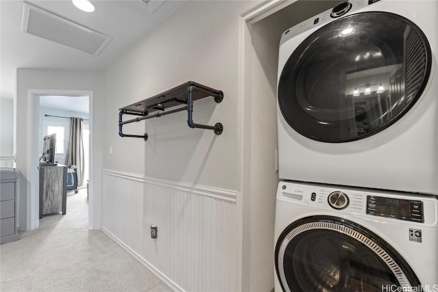 washroom with visible vents, laundry area, attic access, stacked washer / drying machine, and wainscoting