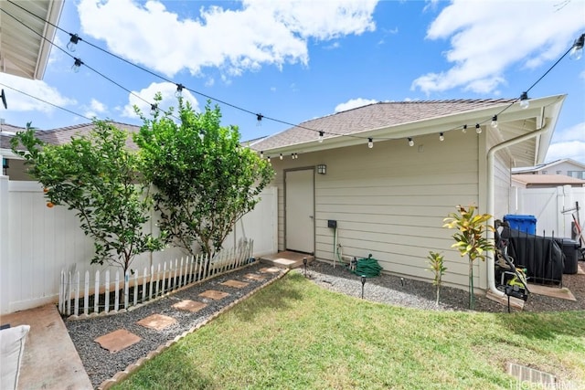 back of house featuring a yard, a fenced backyard, and a shingled roof