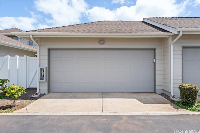 garage featuring driveway and fence