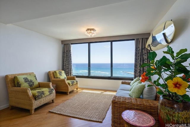 living area with a water view, baseboards, and wood finished floors