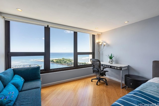 bedroom with a water view, light wood-type flooring, baseboards, and recessed lighting