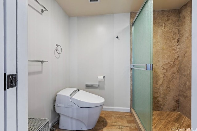 bathroom featuring a stall shower, visible vents, baseboards, and wood finished floors