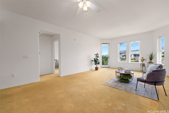 carpeted living area featuring visible vents and ceiling fan