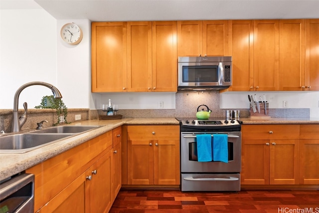 kitchen with brown cabinets, stainless steel appliances, dark wood-type flooring, and a sink