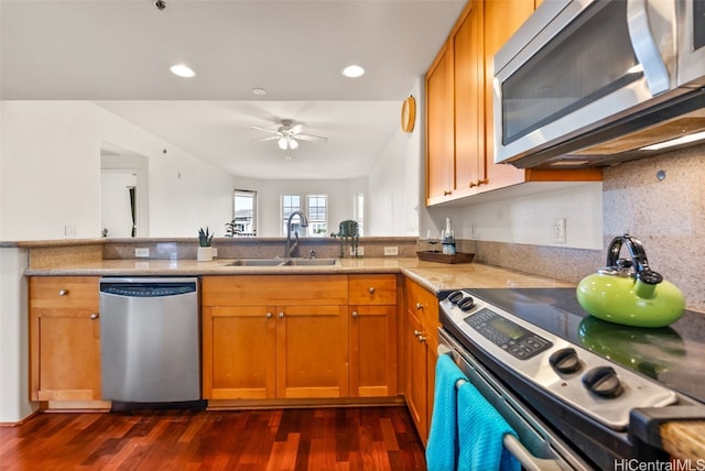 kitchen featuring brown cabinets, a sink, dark wood-style floors, stainless steel appliances, and ceiling fan