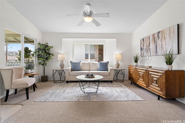 living area featuring light carpet, ceiling fan, and baseboards