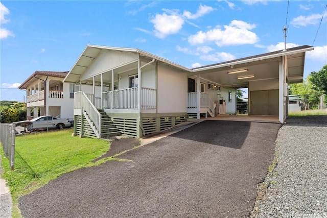 view of front of home with stairway, aphalt driveway, a front lawn, a porch, and a carport