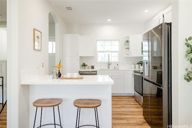 kitchen with stainless steel appliances, white cabinets, light countertops, and a sink