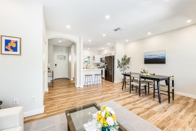 living area featuring arched walkways, recessed lighting, visible vents, baseboards, and light wood-type flooring