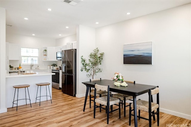 dining area with baseboards, light wood finished floors, visible vents, and recessed lighting