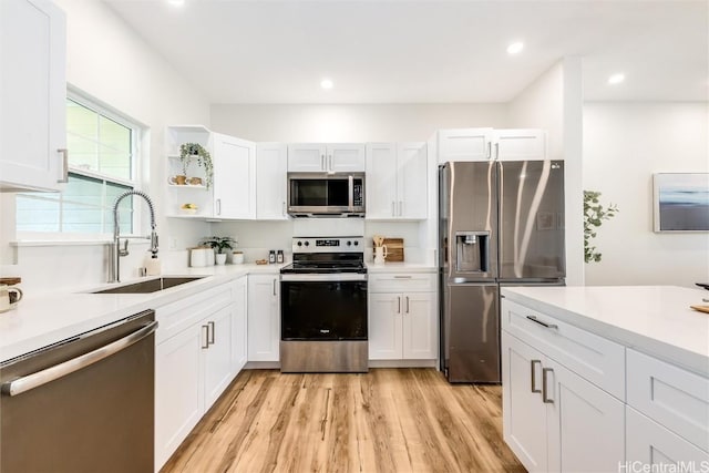 kitchen featuring open shelves, light countertops, appliances with stainless steel finishes, white cabinetry, and a sink