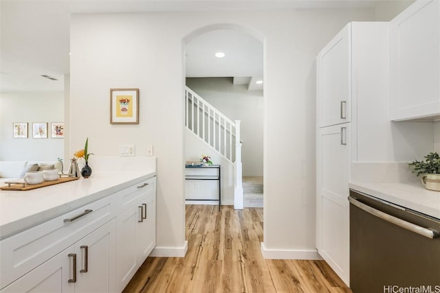 bar with baseboards, dishwasher, light wood finished floors, and stairs