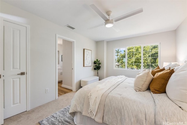 bedroom featuring visible vents, light colored carpet, a ceiling fan, and ensuite bathroom