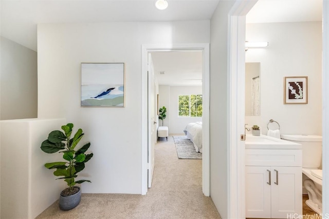 hallway with a sink and light colored carpet