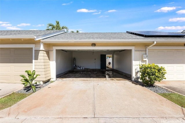 garage featuring solar panels and driveway