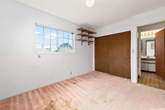 unfurnished bedroom featuring carpet floors, a closet, connected bathroom, and a sink