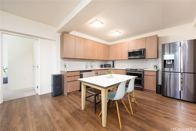 kitchen featuring stainless steel appliances, wood finished floors, and light countertops