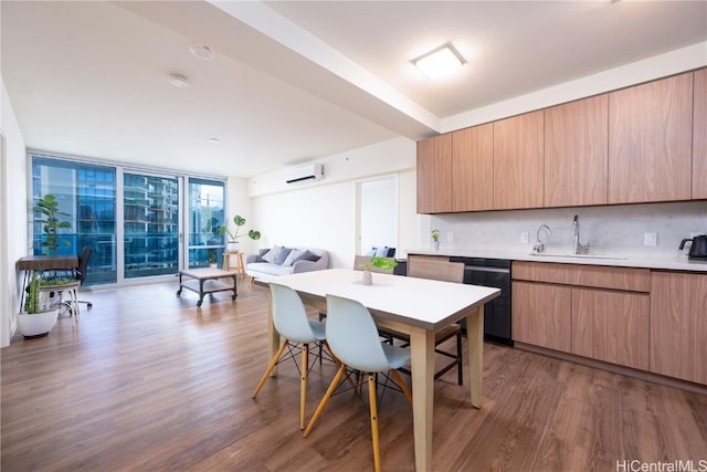 kitchen featuring tasteful backsplash, dark wood-type flooring, a wall of windows, light countertops, and a sink