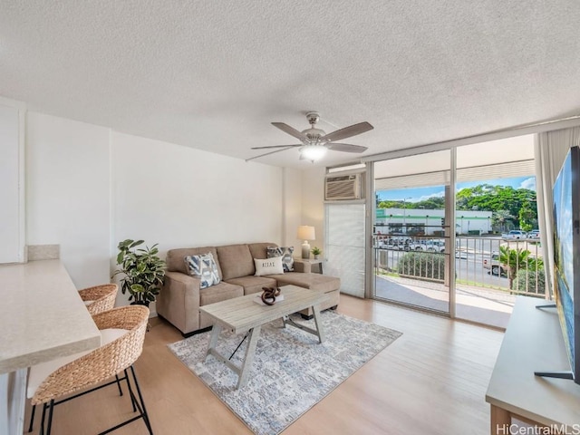 living room featuring a ceiling fan, light wood-type flooring, floor to ceiling windows, and a textured ceiling