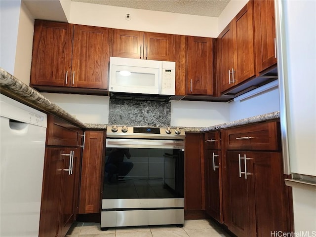 kitchen with white appliances, a textured ceiling, and light tile patterned flooring