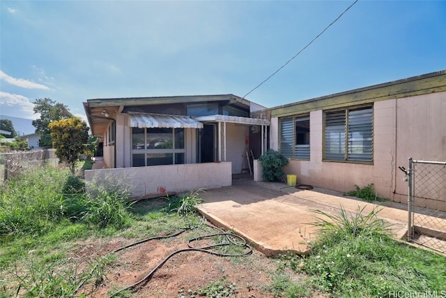 view of front facade featuring concrete block siding, a patio area, and fence