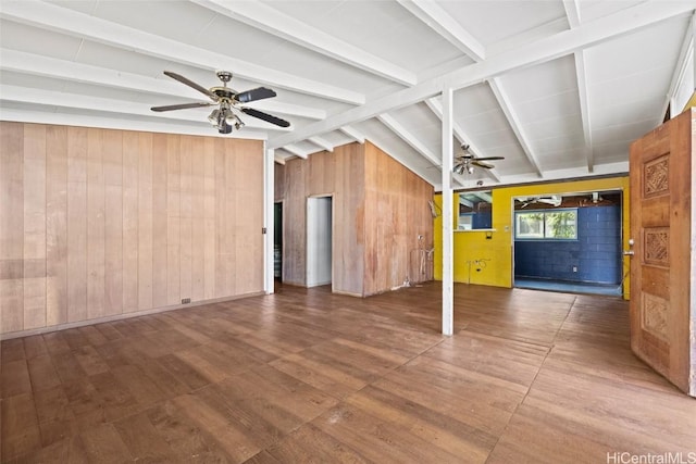 unfurnished living room with ceiling fan, vaulted ceiling with beams, wooden walls, and wood finished floors