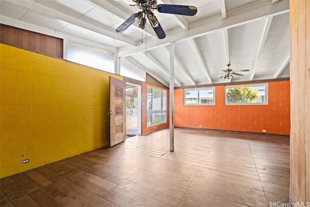 spare room with a ceiling fan, concrete block wall, lofted ceiling with beams, and wood finished floors